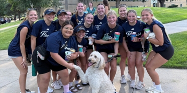Stella the therapy dog poses with student-athletes during an event at College of Saint Mary.