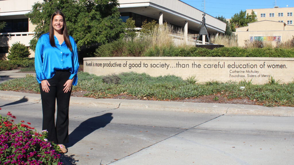 Gillian Cutter stands on campus in front of the Woman Walking statue.