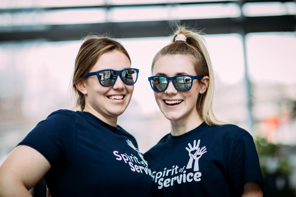 Two students standing together wearing College of Saint Mary Spirit of Service shirts.