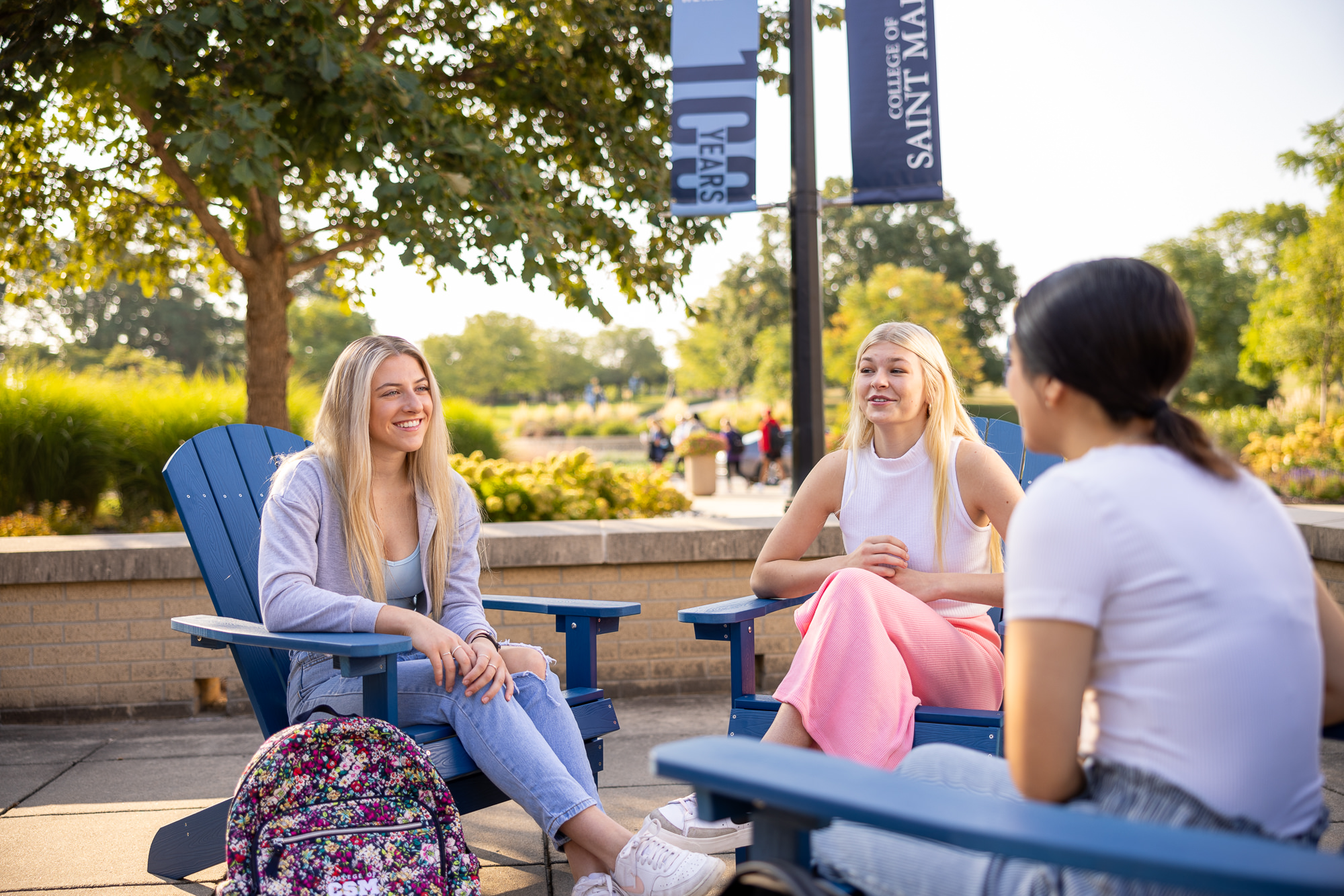 Students hanging out in blue Andirondack chairs in campus plaza at College of Saint Mary.