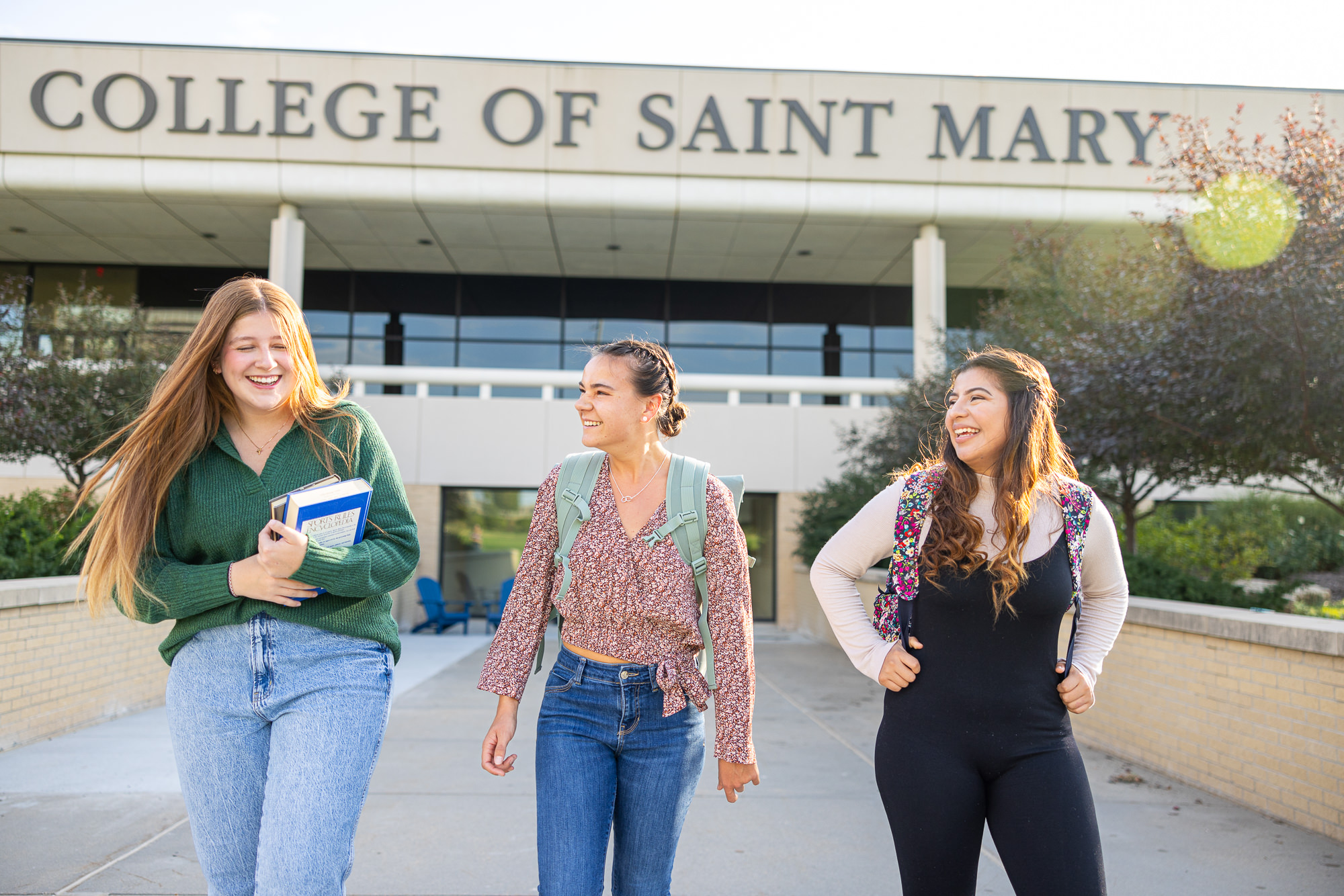 Three College of Saint Mary students walk out of Mercy Hall on campus.