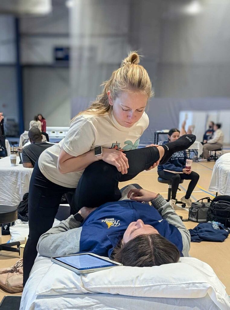 Physical therapy students practicing stretches with another student during on-site campus visit part of the hybrid program at College of Saint Mary.