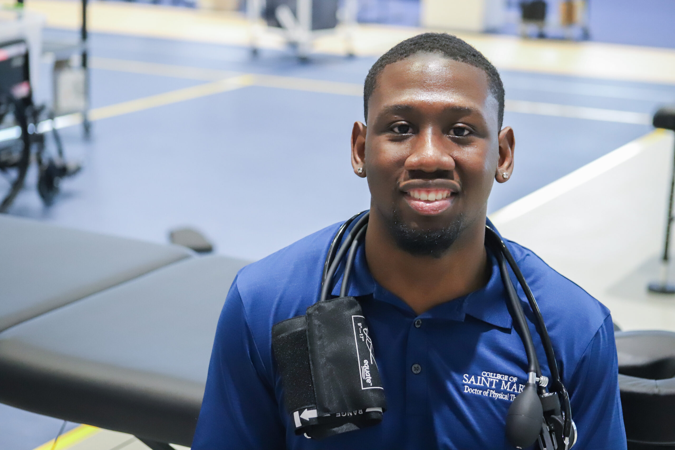 Doctor of Physical Therapy student poses in with blood pressure cuff and monitored hung around his neck.