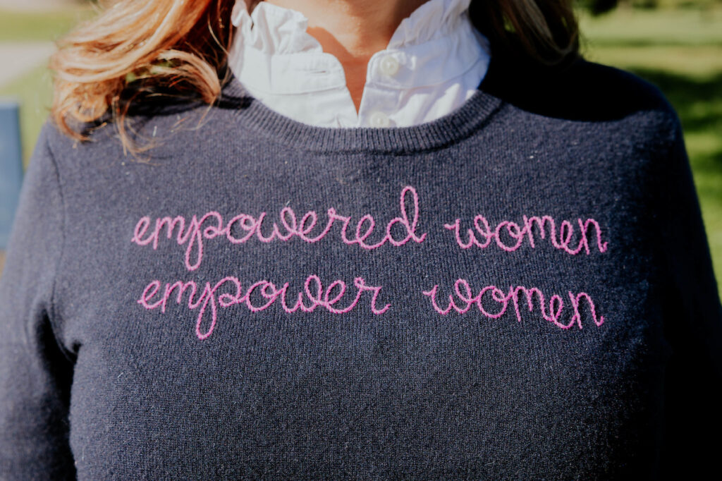 woman wearing a sweater that reads empowered women empower women