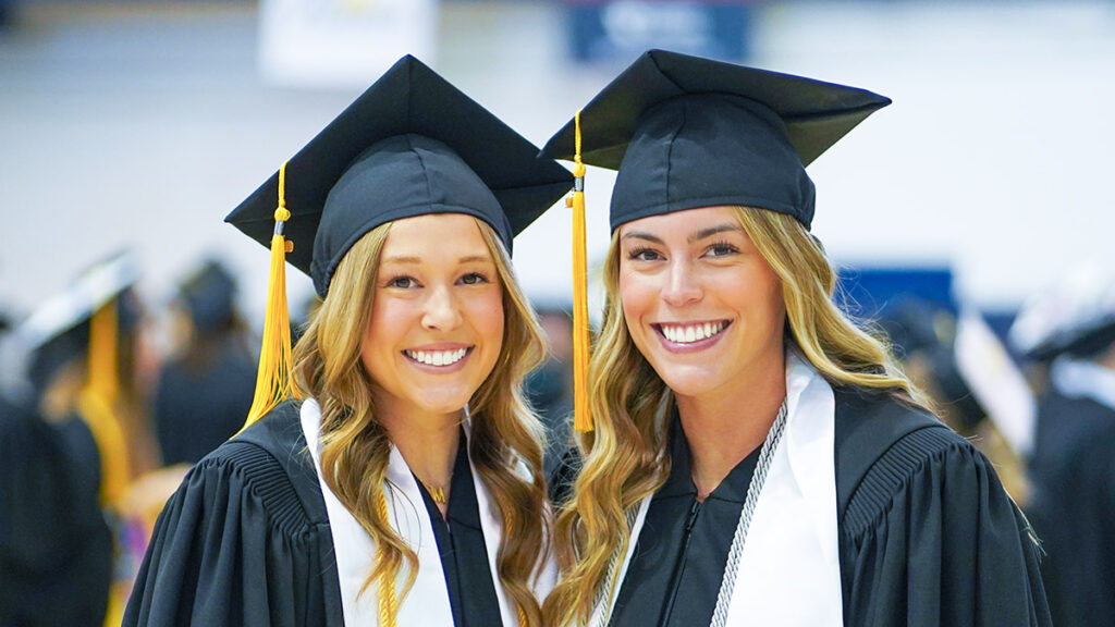 two female graduates smiling at camera