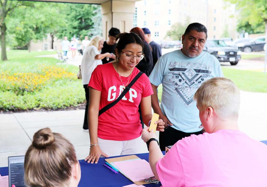 Students checking in at a campus housing table during a move‑in or residence life event.