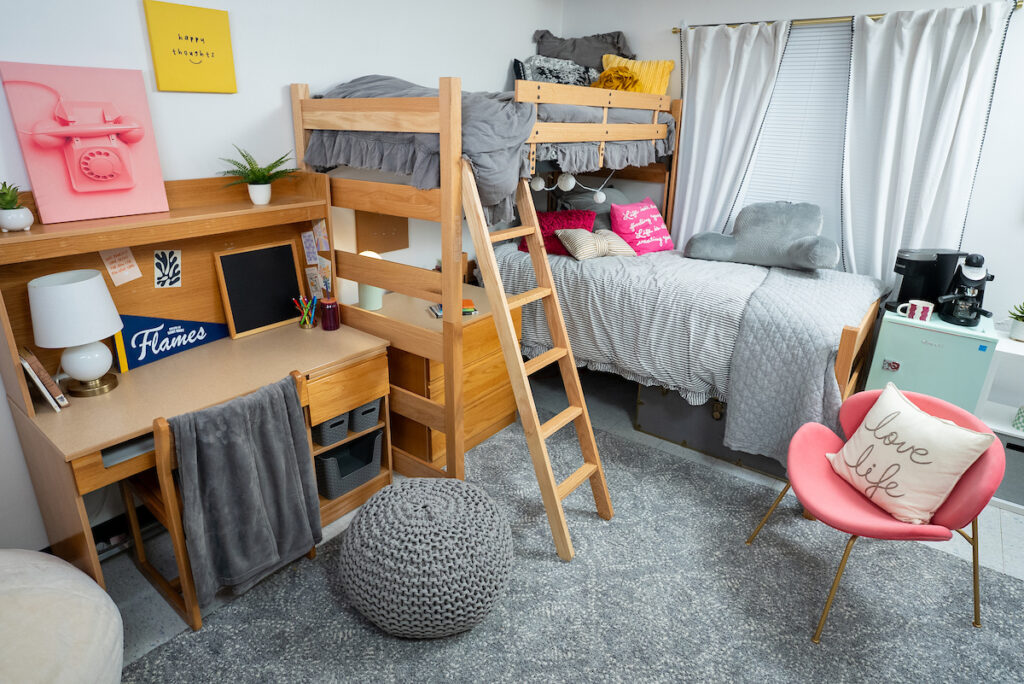 Double‑occupancy room in Lozier Tower featuring bunk beds, two desks, storage space, and seating in a bright, furnished residence hall room.