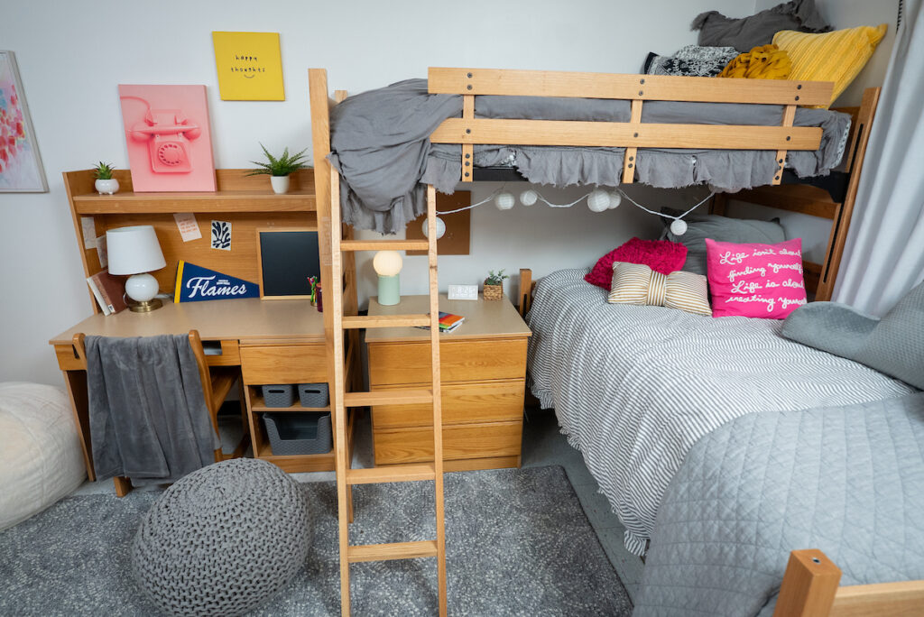 Double‑occupancy room in Lozier Tower featuring bunk beds, two desks, storage space, and seating in a bright, furnished residence hall room.