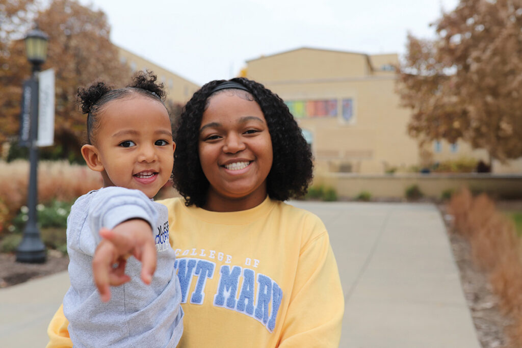 A mother holding her daughter outside campus building
