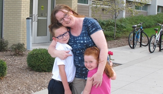 A mother and her two hugging her two children