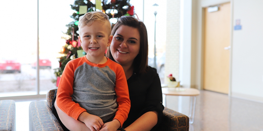 A child sitting on his mothers lap in front of a Christmas tree
