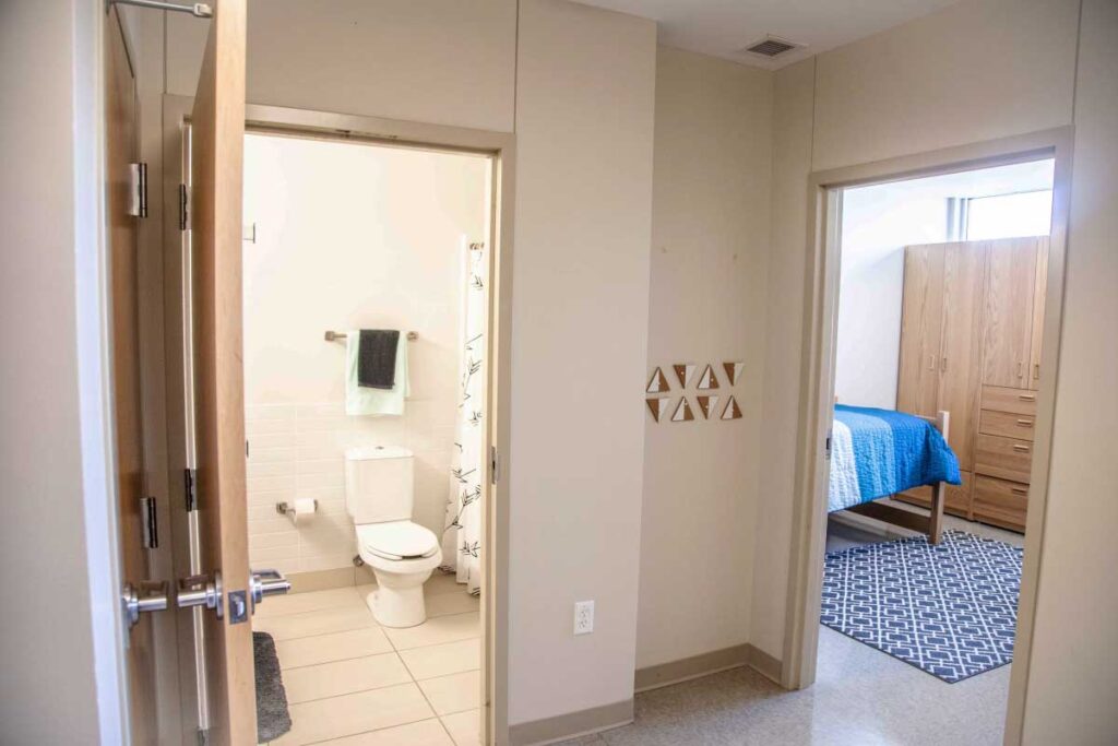 Interior view of Stevens Hall showing a private bathroom and an adjacent bedroom in an apartment‑style residence hall.