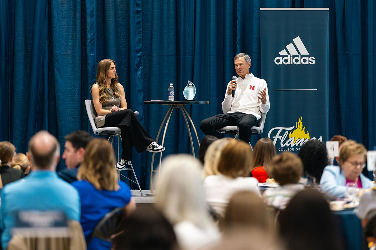 John Cook speaks on stage at Ignite the Flame with an audience in the foreground.