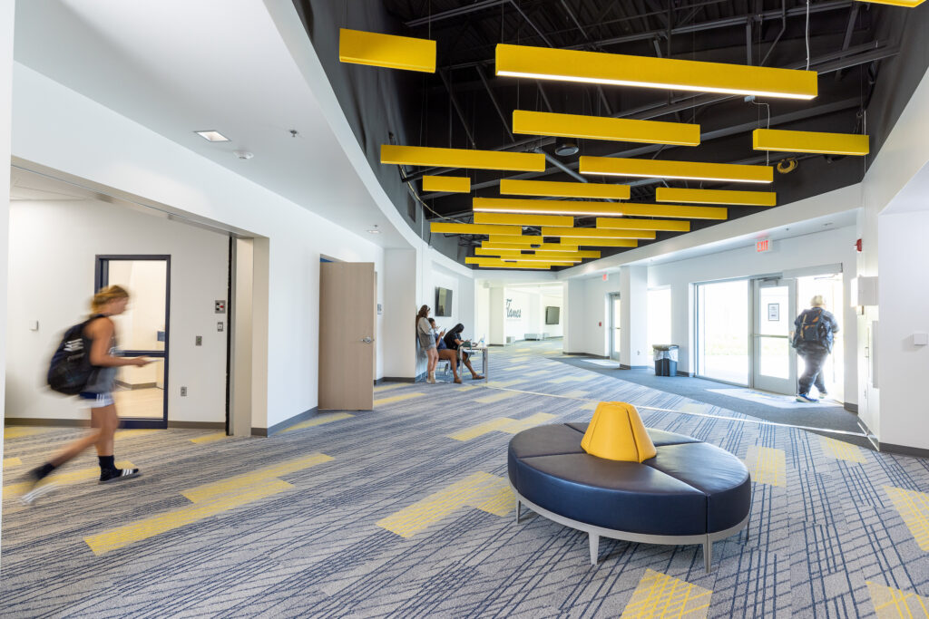 Interior view of College of Saint Mary Lied Fitness Center and Field House facility with students talking and walking.