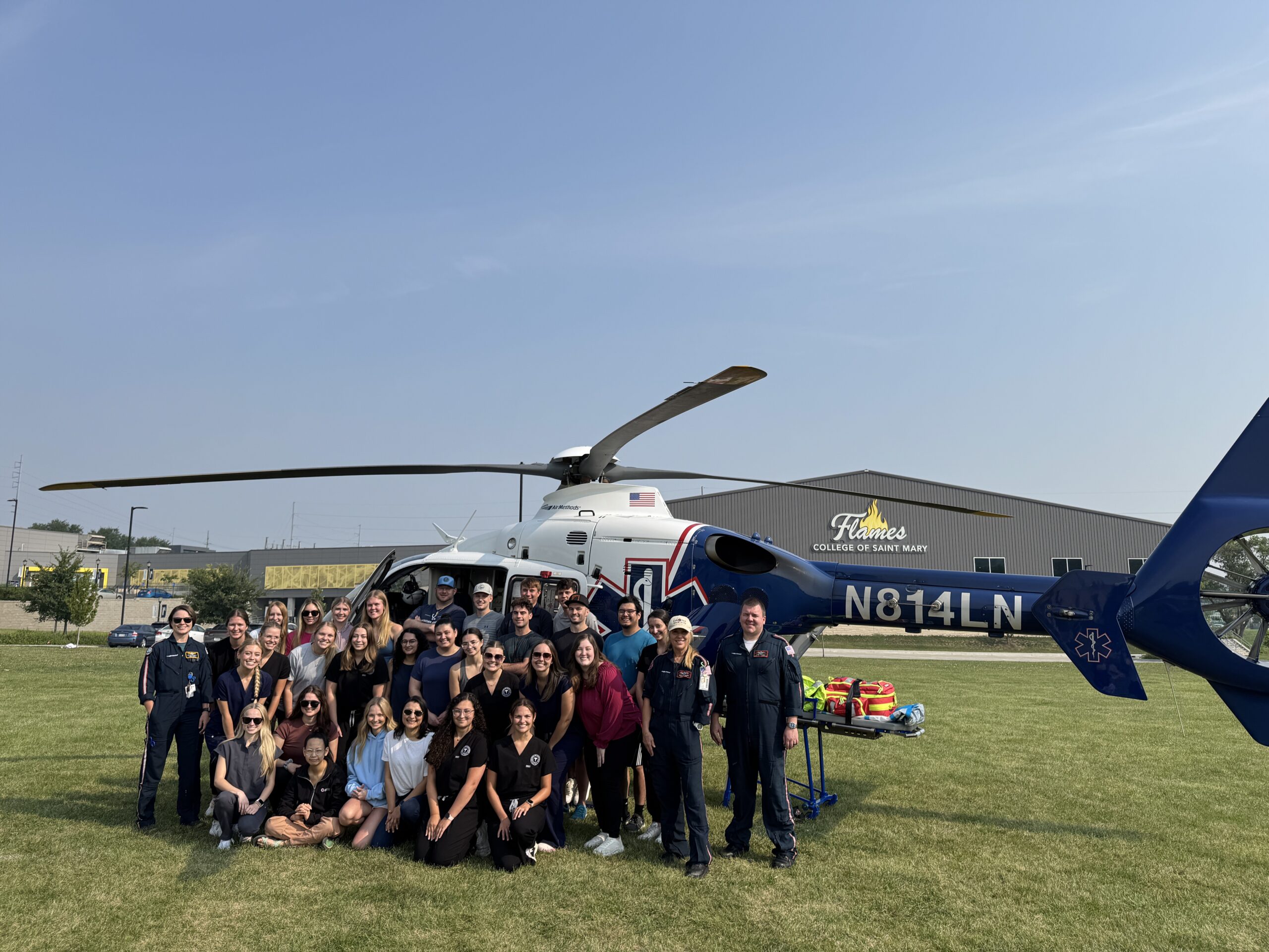 Physician assistant studies students stand in front of a helicopter