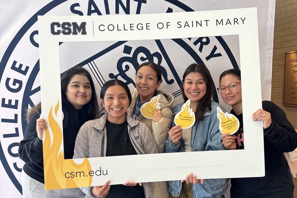 Students pose in front of the CSM seal holding a frame