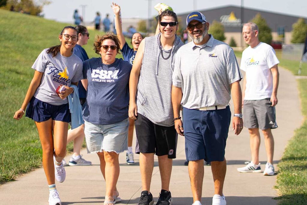 Students and staff walk together on a campus path during Homecoming at College of Saint Mary.
