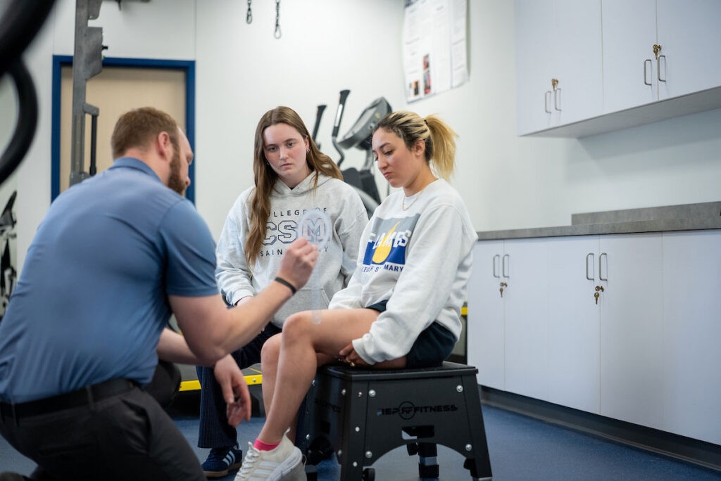 Instructor coaches two students in Kinesiology and Exercise Science lab at College of Saint Mary.