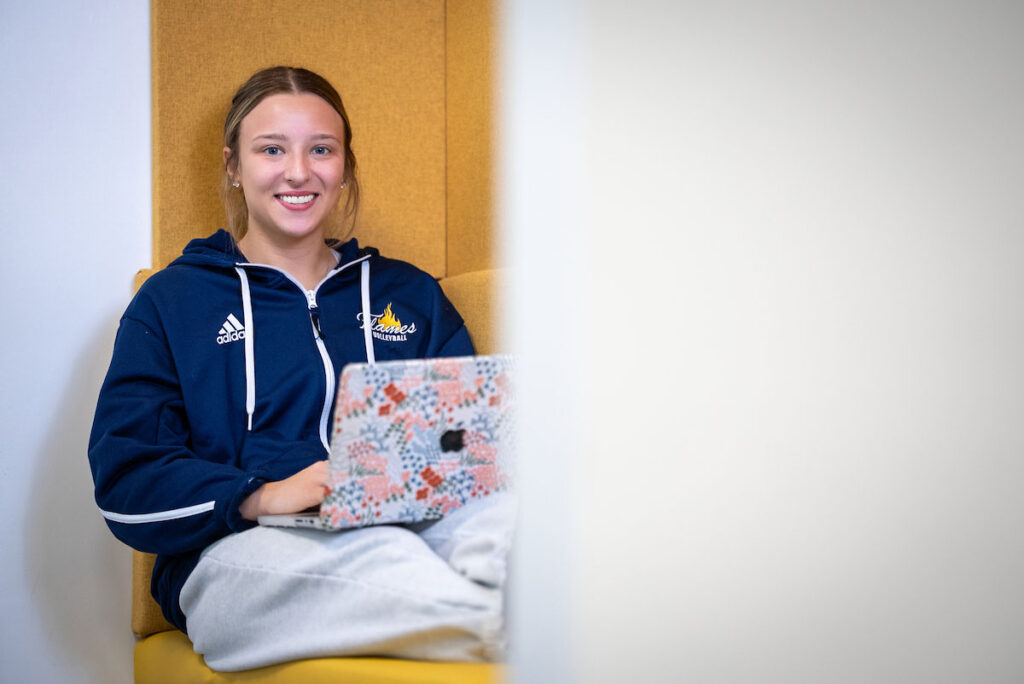 Student in working on a MacBook laptop in a campus study space.