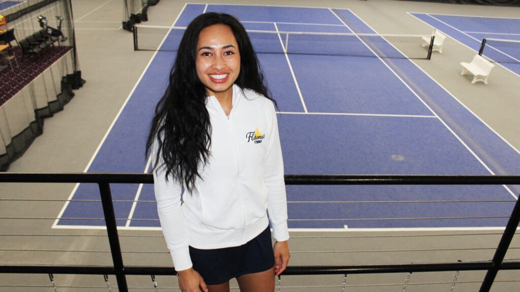 Leah Bailey, College of Saint Mary's tennis coach, stands in front of tennis courts.