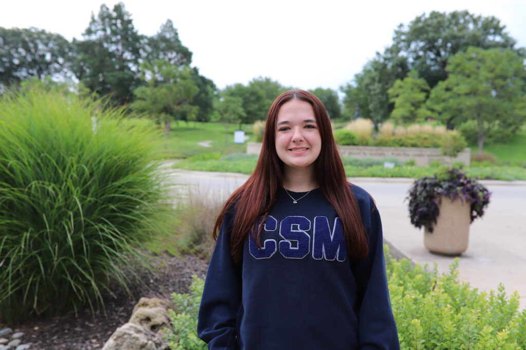 Marie Curie Scholar recipient Brigid Kelly stands in front of the Walking Woman statue on campus.